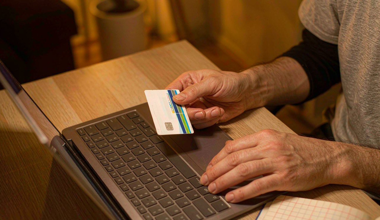 A credit card and a handwritten payment schedule on a desk next to a laptop