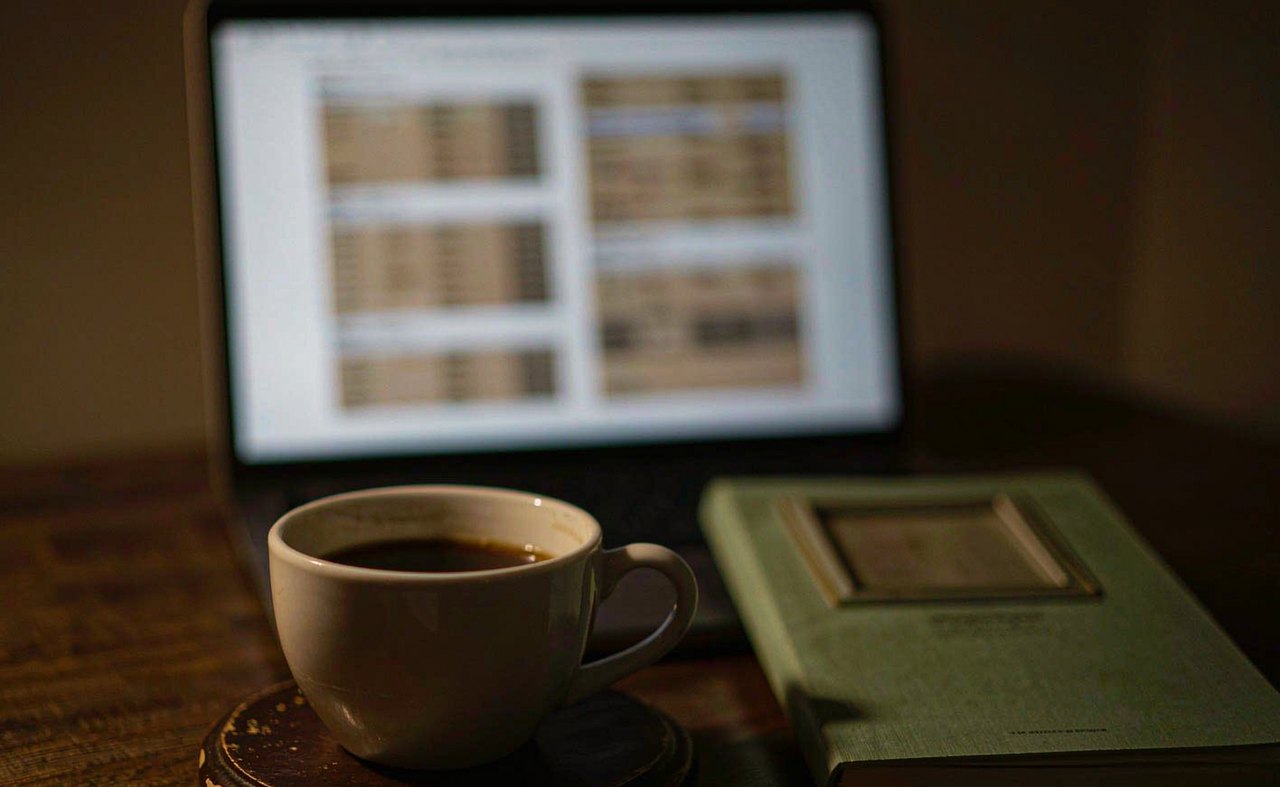 A spreadsheet with two columns of figures beside a cup of coffee on a desk