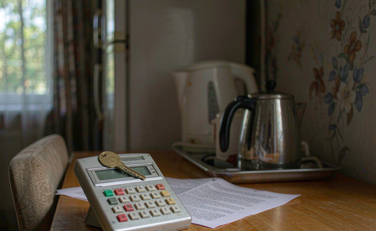 A house key resting on top of a rental lease agreement next to a calculator