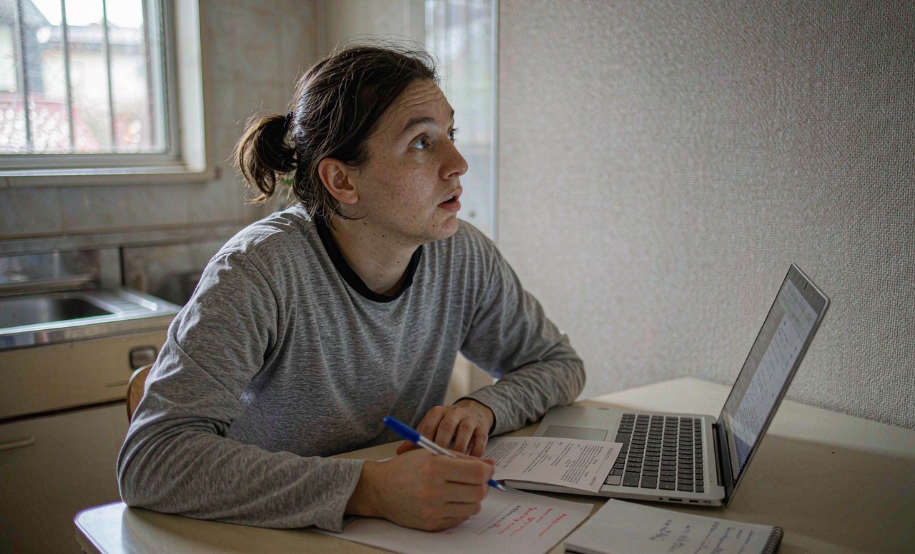 A person reviewing recurring charges on a laptop with a notepad beside them